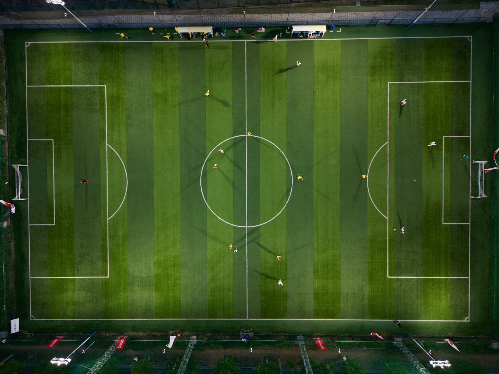 Dynamic aerial shot capturing a soccer match on a vibrant green field at night.